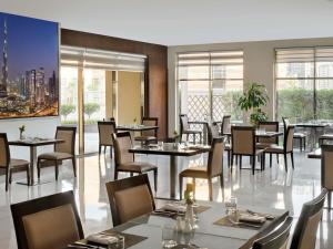 a dining room with tables and chairs and windows at Mövenpick Hotel Apartments Al Mamzar Dubai in Dubai