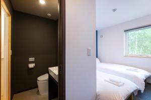 a room with two beds and a toilet and a window at Hirafu Tomten in Kutchan +16 photos