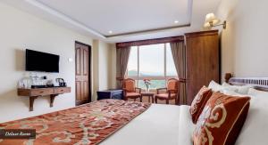 a hotel room with a bed and a desk and a television at Summit Hermon Hotel & Spa in Darjeeling