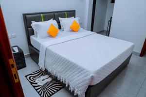 a bed with orange and white pillows in a room at Martin Aviator Hotel in Kigali