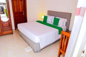 a bedroom with a large white bed with green accents at Martin Aviator Hotel in Kigali +11 photos