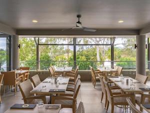 a dining room with tables and chairs and windows at Mercure Rockhampton in Rockhampton