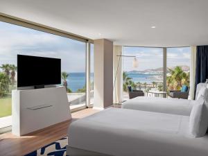 a hotel room with two beds and a large window at Swissôtel Resort Bodrum Beach in Turgutreis