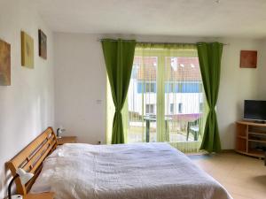 Schlafzimmer mit einem Bett und einem Fenster mit grünen Vorhängen in der Unterkunft Apart Riviera Lipno J4-12 in Lipno nad Vltavou