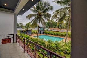 a balcony with a swimming pool and palm trees at Orange Vista Resort Coorg in Kushālnagar