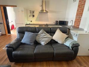 a black leather couch with pillows on it in a kitchen at Woodside Cottage in Newtown +10 photos