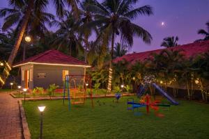 a playground in front of a house with palm trees at Orange Vista Resort Coorg in Kushālnagar
