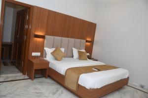 a bedroom with a large bed with a wooden headboard at Hotel gardenia inn in Gwalior