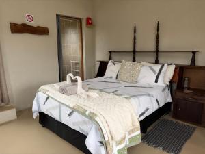 a bedroom with a large bed and a dresser with a bedskirts at Shama Lodge - "Silent Sunsets" Duplex Cottage in Steytlerville