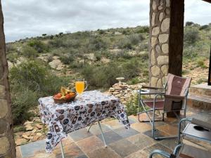 a table with a bowl of fruit and a glass of orange juice at Shama Lodge - "Silent Sunsets" Duplex Cottage in Steytlerville