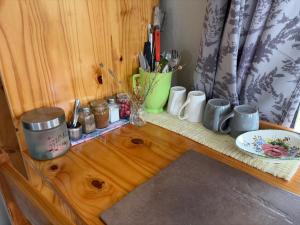a wooden counter with a shelf with dishes and utensils at Shama Lodge - "Silent Sunsets" Duplex Cottage in Steytlerville