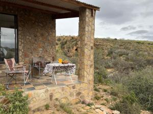 a stone house with a table and chairs on a porch at Shama Lodge - "Silent Sunsets" Duplex Cottage in Steytlerville +11 photos