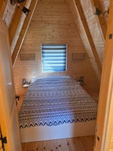 a bed in a wooden room with a window at durmitor's golden peace in Šavnik