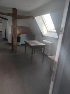 an attic room with a table and a window at Logement à la ferme in Bréauté +6 photos