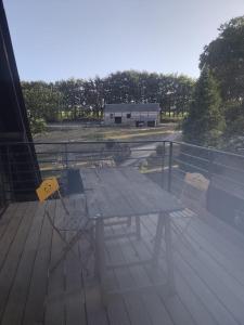 a picnic table and two chairs on a deck at Logement à la ferme in Bréauté