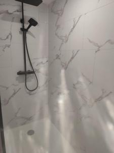 a bathroom with a shower with white marble walls at Logement à la ferme in Bréauté