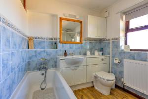 a bathroom with a tub and a toilet and a sink at Garth Cottage in Gwaynynog +32 photos