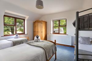 a bedroom with two beds and two windows at Garth Cottage in Gwaynynog