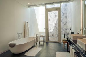 a white bathroom with a tub and a sink at Al Zorah Beach Resort in Ajman 