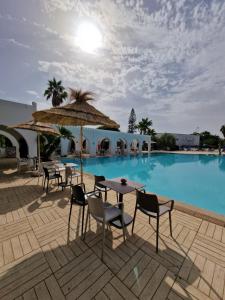 a pool with tables and chairs and an umbrella at Seabel Alhambra Beach Golf & Spa in Port El Kantaoui