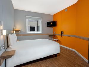 a bedroom with a white bed and orange walls at ibis budget Lima Miraflores in Lima