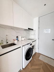 a white kitchen with a washing machine and a sink at Studio Apartment by Sunshine Beach in Layan Beach