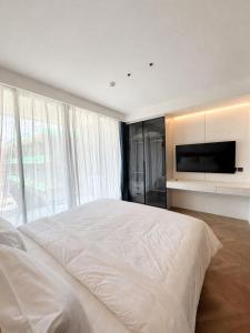 a bedroom with a large bed and a flat screen tv at Studio Apartment by Sunshine Beach in Layan Beach