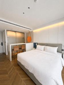 a bedroom with a large white bed and a table at Studio Apartment by Sunshine Beach in Layan Beach