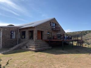 a brick house with a porch and a deck at Shama Private Group Lodge in Steytlerville