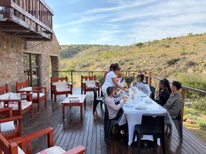 a group of people sitting at a table on a deck at Shama Private Group Lodge in Steytlerville