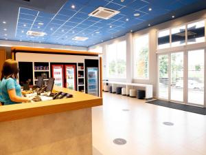 a woman standing at a counter in a store at ibis budget Leme SP in Leme