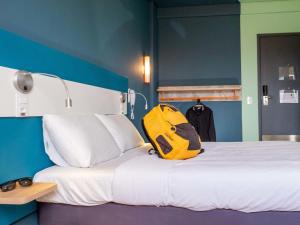 a yellow backpack sitting on top of a bed at ibis budget Leme SP in Leme +58 photos