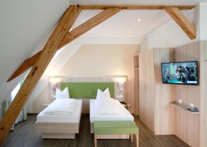 a bedroom with two beds and a tv on the wall at Schwarzwald Apartments Fürstenberg in Hüfingen