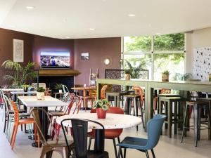 a restaurant with tables and chairs and a tv at Greet Hôtel Castres Saix in Saix