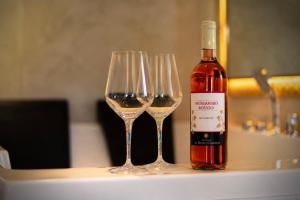 a bottle of wine and three wine glasses on a table at Aphrodeseum Romantic Suite in Taranto