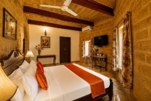 a bedroom with a large bed and a television at WelcomHeritage Mohangarh Fort in Sodākor