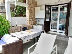 a patio with a table and chairs and a kitchen at Damir Apartments Bonina in Jelsa
