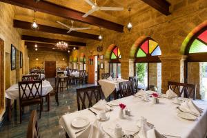 a dining room with tables and chairs and windows at WelcomHeritage Mohangarh Fort in Sodākor