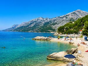a beach with a group of people on the water at Rooms Jakirusa in Brela