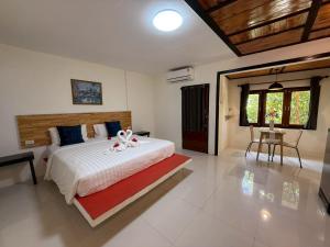 a bedroom with a large bed with two white flowers on it at Mookboonchu Guesthouse ,Kohmook Trang in Ko Mook +144 photos
