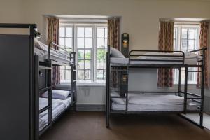 a room with three bunk beds and a window at YHA Ilam Hall in Ashbourne