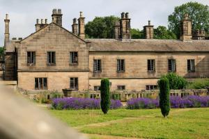 an old stone building with trees in front of it at YHA Ilam Hall in Ashbourne