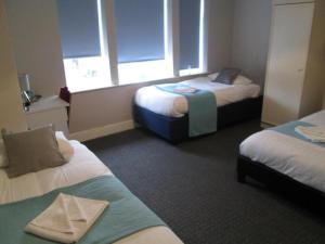 a hotel room with two beds and two windows at Paramount Hotel in Nottingham