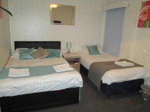 a hotel room with two beds and a mirror at Paramount Hotel in Nottingham