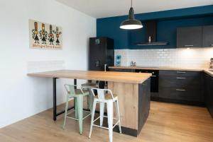 a kitchen with a wooden table and two stools at Le tie-break in Pont-Croix