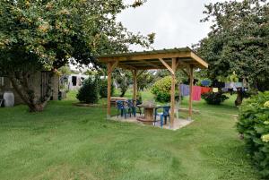 a gazebo with a table and chairs in a yard at Le tie-break in Pont-Croix