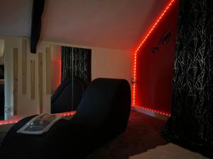 a room with a black chair and red lights at Le Petit Quiou in Le Quiou