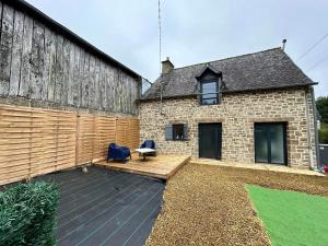 a backyard with a wooden deck next to a building at Le Petit Quiou in Le Quiou