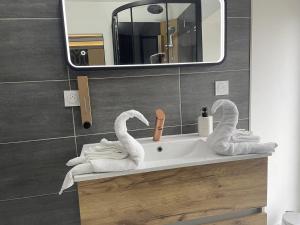 a bathroom with a sink with swans towels on it at Le Petit Quiou in Le Quiou +6 photos