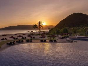 a resort pool with chairs and umbrellas on the beach at Pullman Lombok Merujani Mandalika Beach Resort in Kuta Lombok